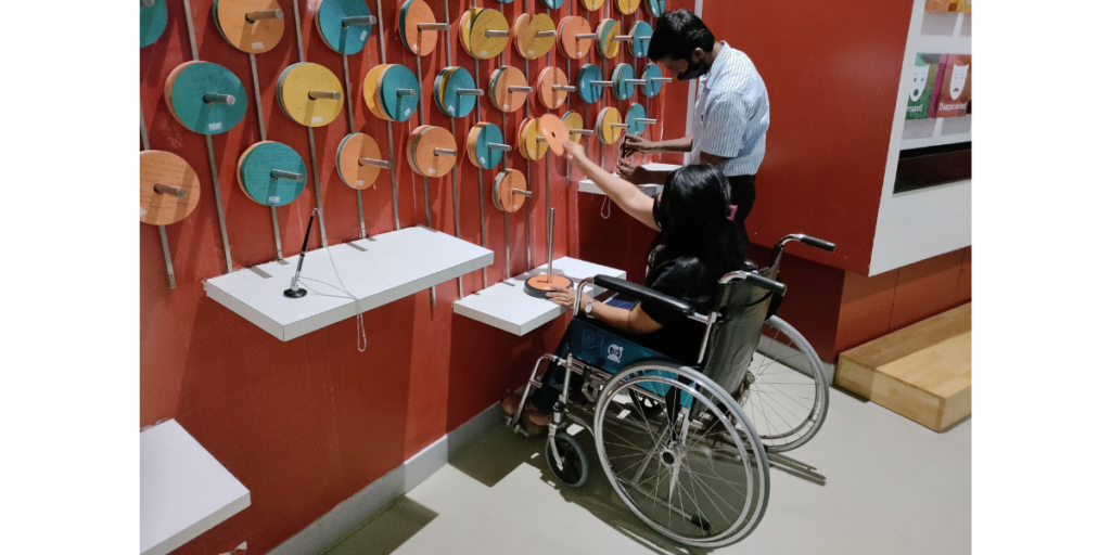 Woman in a wheelchair and a man interacting with a gallery at a museum